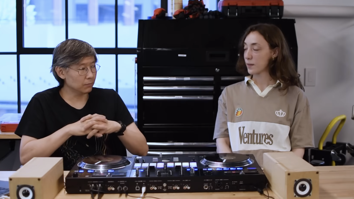 A man and a woman sitting at a table, in a sound lab, are discussing the history of dub music.