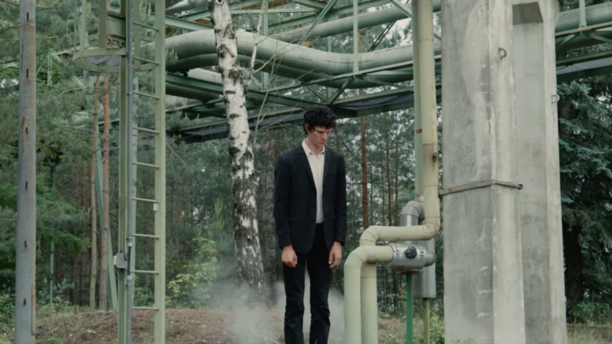 Video for Die Verlierer - Notausgang. A band member stares, defeated, at the floor in an industrial setting.